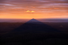 Load image into Gallery viewer, Didthul (Pigeon House Mountain) at sunset with its iconic peak glowing orange above the ocean, casting a dramatic shadow across the coastal landscape in South Coast NSW.
