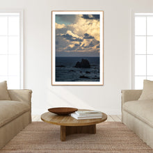 Load image into Gallery viewer, Living room with a framed artwork of glasshouse rocks in narooma south coast by Greg selby, beige sofa, wooden coffee table, and books. 