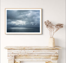 Load image into Gallery viewer, Framed artwork of a stormy sky over water on a wall above a wooden mantelpiece with a vase of dried flowers. Greg Selby coastal decor