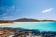 Load image into Gallery viewer, Stunning coastal photograph of Murrunna Point in Bermagui on a clear sunny day, featuring crystal-blue ocean waters, bright skies, and Gulaga Mountain gently rising in the background. wallaga lake